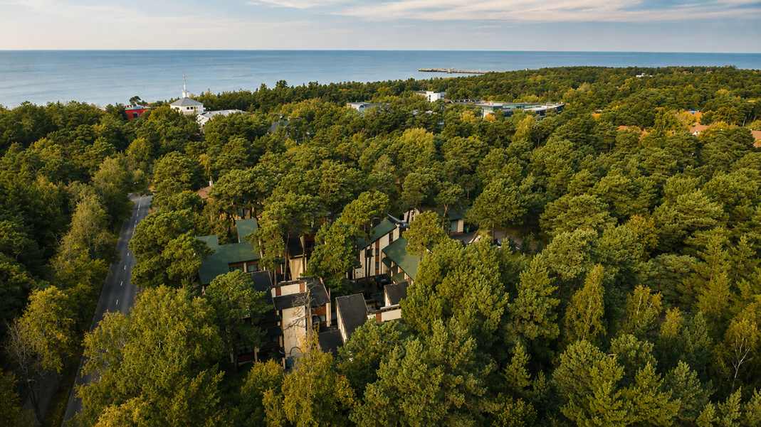 Aerial view of Palanga Park Hotel nestled in a lush pine forest with the Baltic Sea in the distance